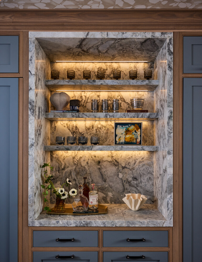 Illuminated marble bar with integrated shelving and floral decor in a custom San Francisco home by S.A. Baxter, Inc.