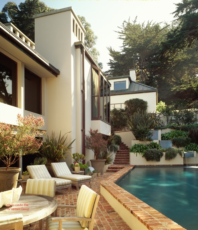 Elevated pool deck with red brick pavers and lush greenery in Carmel Highlands custom home by S.A. Baxter, Inc.