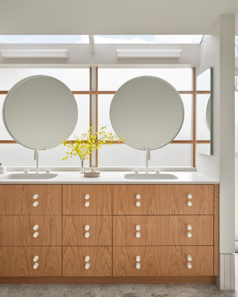 Symmetrical bathroom vanity with round mirrors and modern wood drawers in a Marin County home by S.A. Baxter, Inc.