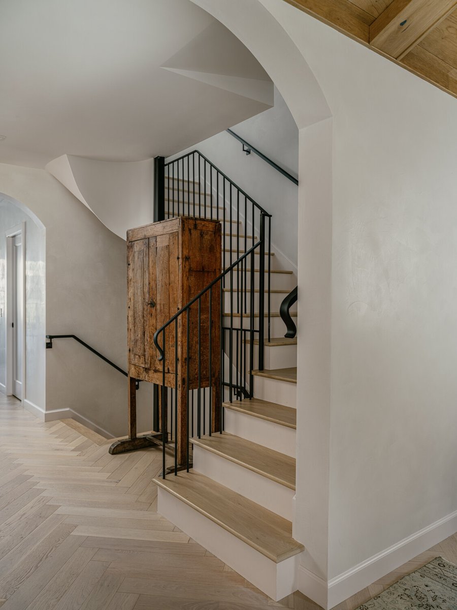 Elegant staircase with arched entry and natural wood flooring in Marina District custom home by S.A. Baxter, Inc.