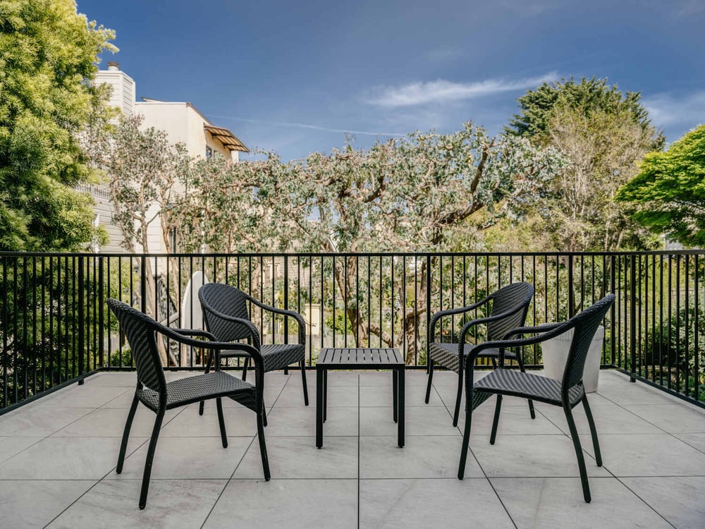 Outdoor terrace with black patio chairs and lush greenery by S.A. Baxter, Inc. in Marina District custom home