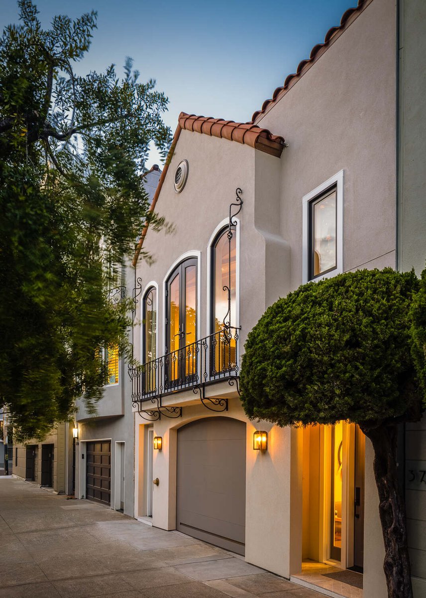 Spanish-style custom home facade with iron balcony and soft evening lighting in Marina District by S.A. Baxter, Inc.