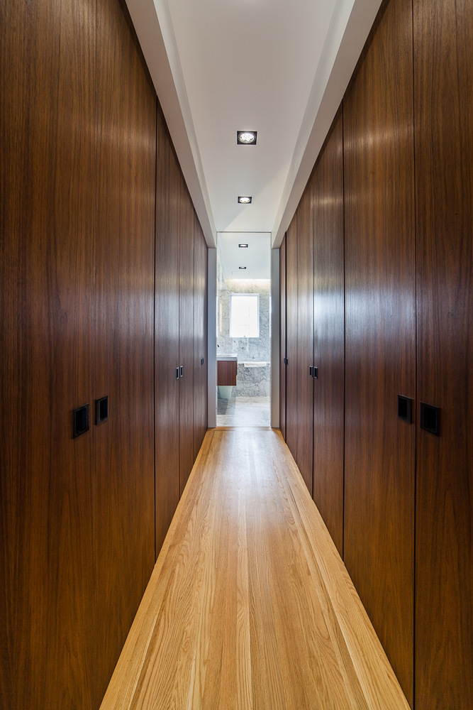 Wood-paneled hallway with recessed lighting leading to marble bathroom in Nob Hill home by S.A. Baxter, Inc.