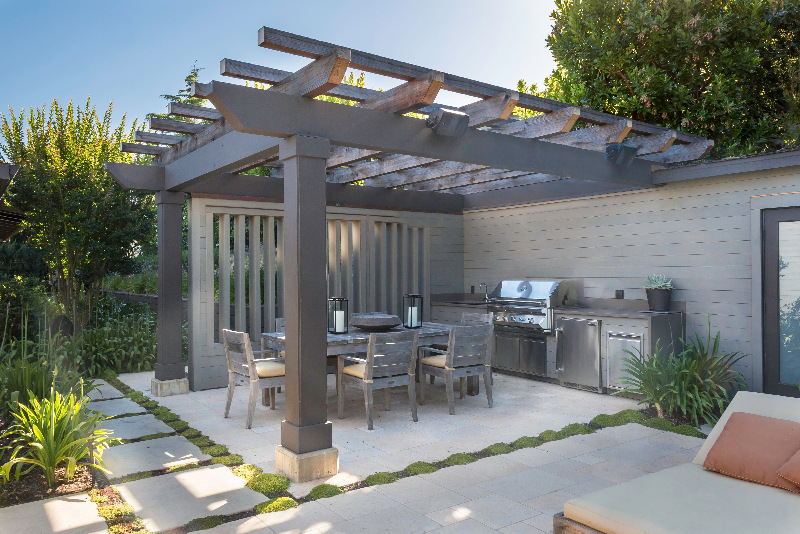 Covered outdoor kitchen and dining space with wood pergola in Tiburon home by S.A. Baxter, Inc.