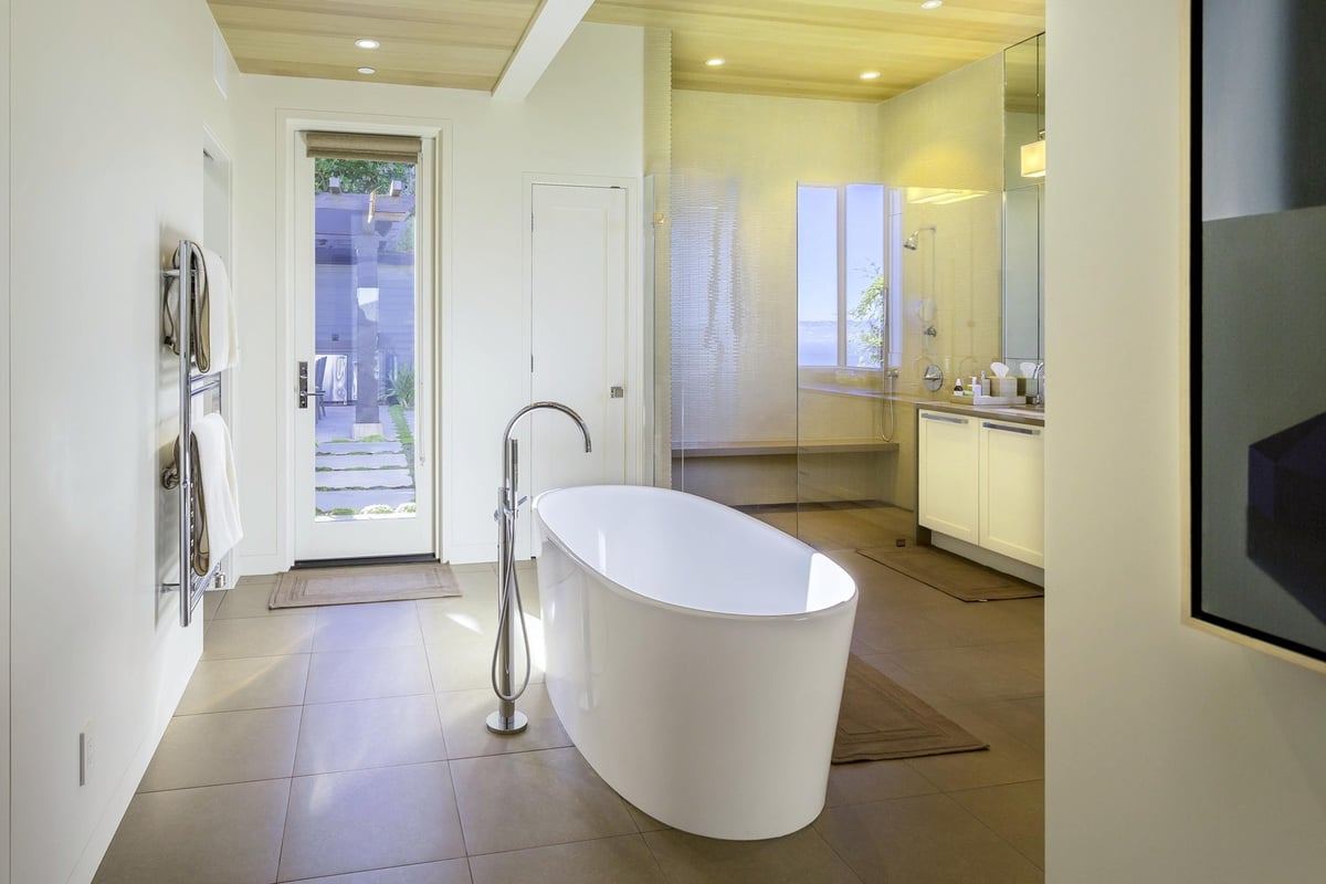 Light-filled bathroom with soaking tub and access to garden in Tiburon custom home by S.A. Baxter, Inc.